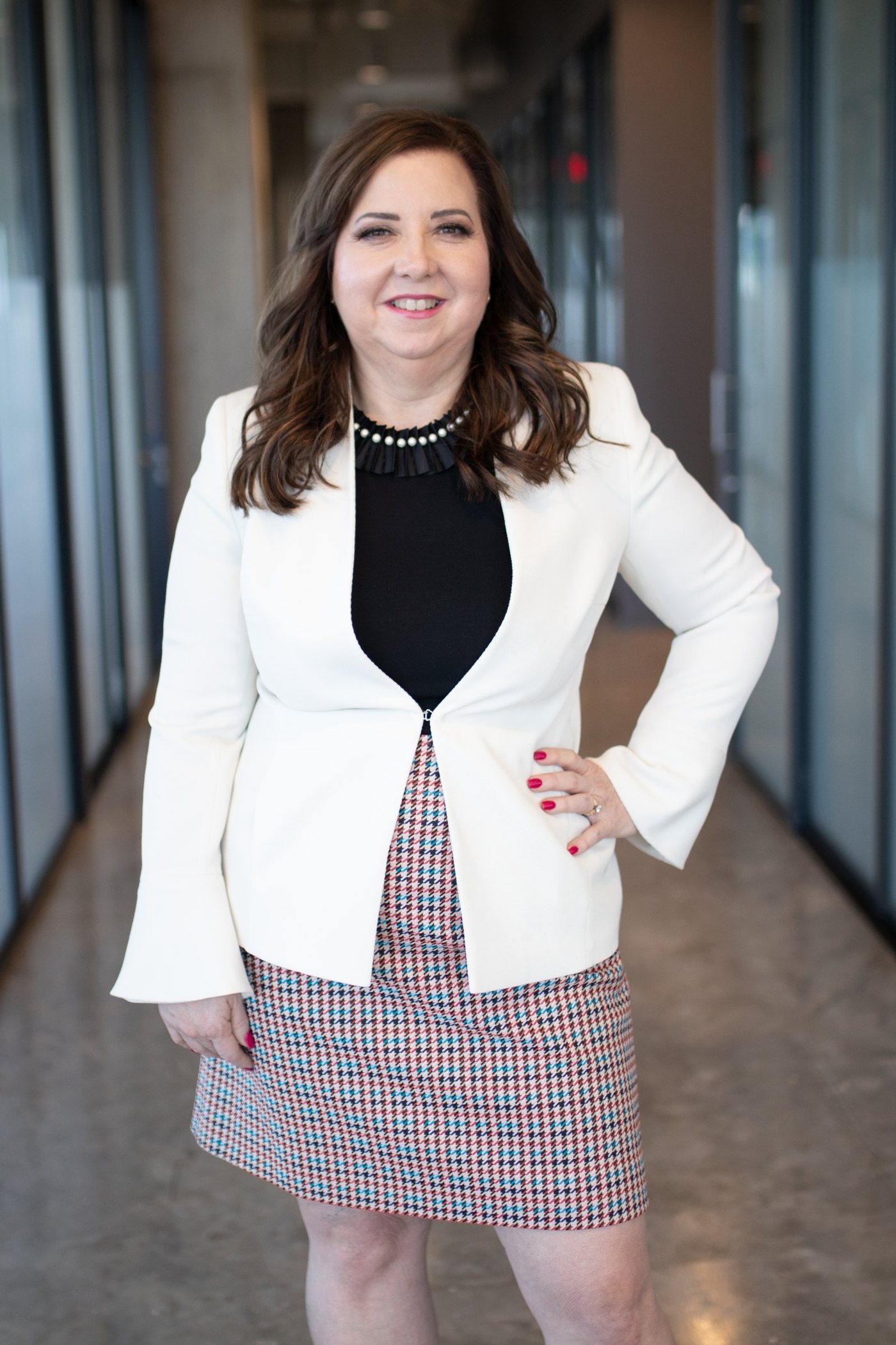 Deborah Daniel, CPA, standing in the hallway of the Charter Accounting office in a white blazer